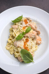 Pasta with salmon, cream sauce and basil on a white plate