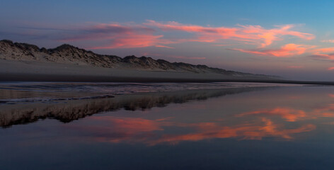 Sunset landscape of the Viago beach in Pedrogao, Figueira da Foz, Portugal, with the clouds reflected on the water.