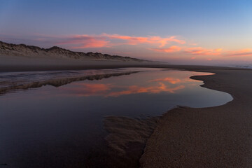 Sunset landscape of the Viago beach in Pedrogao, Figueira da Foz, Portugal, with the clouds reflected on the water.