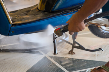 Worker polishing a car with high pressure washer closeup