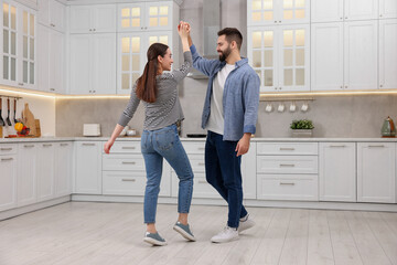 Happy lovely couple dancing together in kitchen