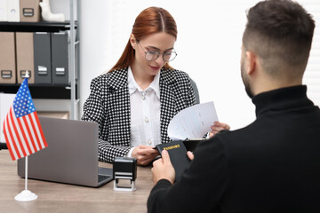 Immigration to United States of America. Embassy worker checking man's documents in office