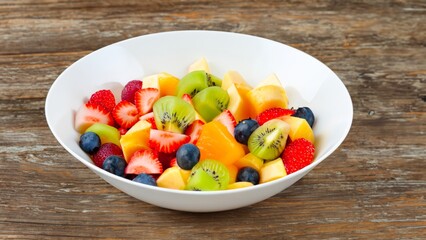 fruit salad in a white bowl on wooden table