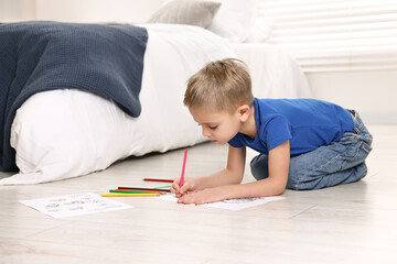 Cute little boy coloring on warm floor at home. Heating system