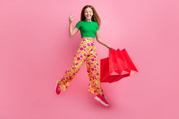 Full length photo of cheerful positive cute girl fly air wear trendy clothes hand v-sign isolated on pink color background
