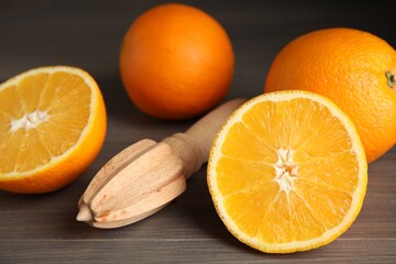 Fresh ripe oranges and reamer on wooden table, closeup