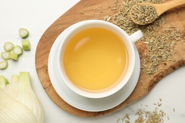 Fennel tea in cup, seeds and fresh vegetable on white marble table, flat lay