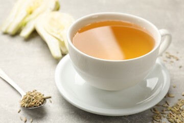 Aromatic fennel tea, seeds and fresh vegetable on grey table, closeup