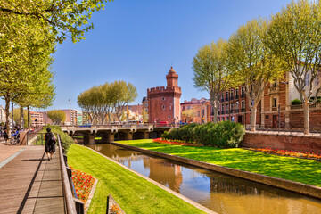 La Basse, a tributary of the Tet, which crosses the French city of Perpignan, Languedoc-Roussillon,  and the Porte du Notre Dame. - obrazy, fototapety, plakaty