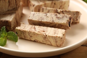 Tasty chocolate halva with mint on wooden table, closeup