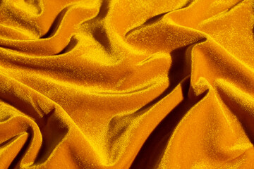 Velvet fabric of rich amber yellow orange color, soft, warm texture, creative background.