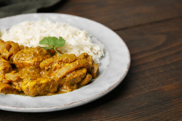 Delicious chicken curry with rice on wooden table, closeup