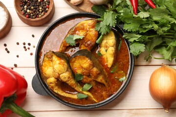 Tasty fish curry and ingredients on white wooden table, flat lay. Indian cuisine