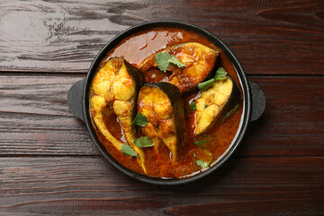 Tasty fish curry on wooden table, top view. Indian cuisine