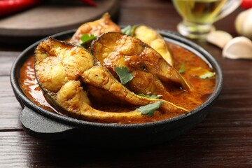 Tasty fish curry on wooden table, closeup. Indian cuisine