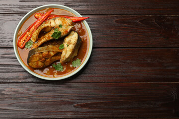 Tasty fish curry on wooden table, top view. Space for text. Indian cuisine