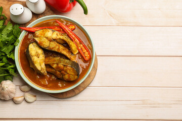 Tasty fish curry and ingredients on white wooden table, flat lay. Space for text. Indian cuisine