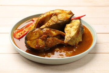 Tasty fish curry on white wooden table, closeup. Indian cuisine