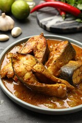 Tasty fish curry and ingredients on grey textured table, closeup. Indian cuisine