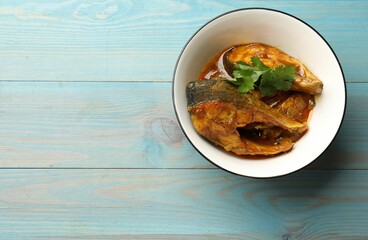 Tasty fish curry on light blue wooden table, top view. Space for text. Indian cuisine