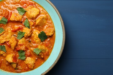 Delicious chicken curry on blue wooden table, top view. Space for text