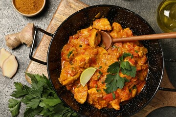Delicious chicken curry and ingredients on grey table, flat lay
