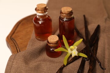 Aromatic vanilla extract, pods and flower on tablecloth, closeup