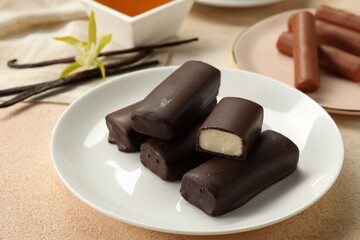 Glazed vanilla curd cheese bars served on beige table, closeup