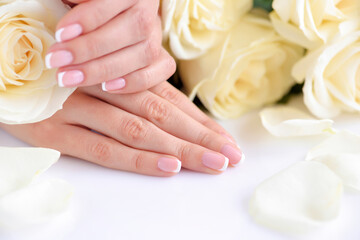 Hands of a woman with beautiful french manicure and white roses