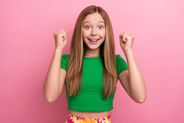 Photo of cheerful glad girl wear green clothes raise hands fists celebrate holiday isolated on pink color background