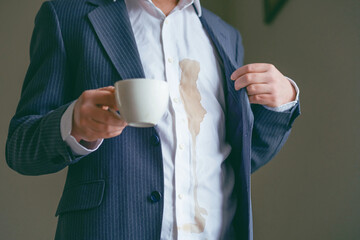 Unrecognizable a man in a suit spilled coffee on a white shirt in cafe. Dirty brown coffee stain on clothes. daily life stain concept