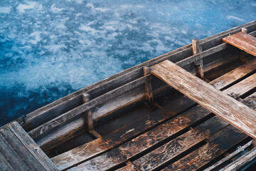 Close up of a wooden rowboat on the frozen lake.