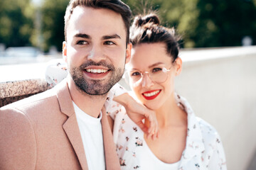 Beautiful fashion woman and her handsome elegant boyfriend in beige suit. Sexy brunette model in summer clothes. Fashionable smiling couple posing in street Europe. Brutal man and female outdoors