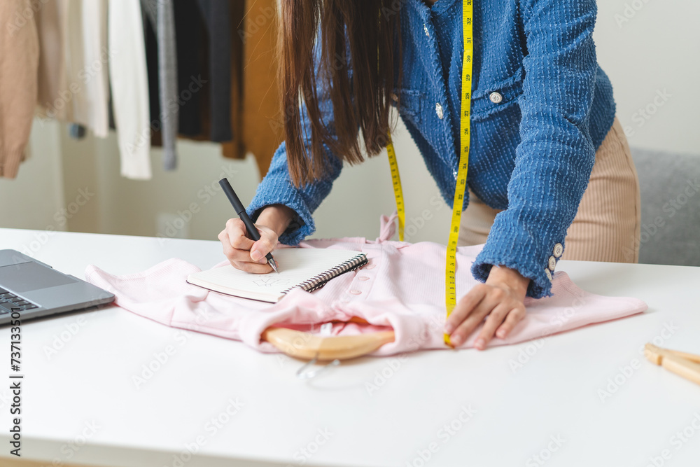 Wall mural Young small business woman prepare used clothes to sell on internet.