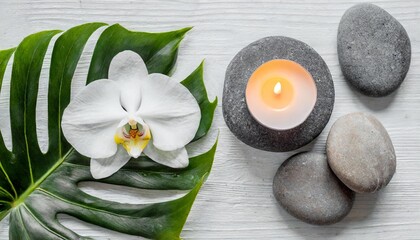 Fototapeta na wymiar spa stones palm leaves flower white orchid candle and zen like grey stones on white background flat lay top view