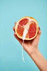  object photo of fresh juicy grapefruit with tampon in it in hand of unknown woman on blue backdrop © LIGHTFIELD STUDIOS