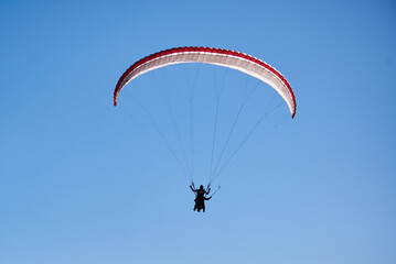 A paraglider soars alone in the endless blue sky