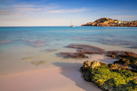 view of the idyllic bay and beach of Cala Agulla in eastern Mallorca with a sailboat in the foreground