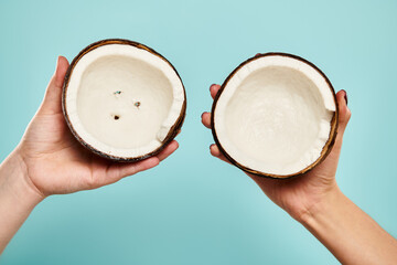 object photo of gourmet fresh coconut in hands of young unknown female model on blue background