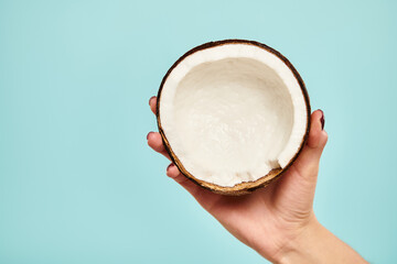 object photo of delicious piece of coconut in hand of young unknown woman on vibrant blue backdrop