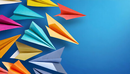 Colorful origami paper planes on blue background with copy space