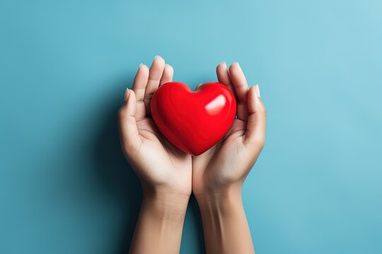 hand holding a red heart on a blue background