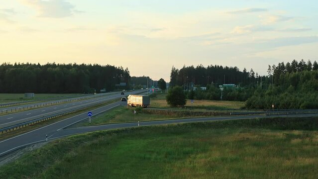 Tautliner A-frame drawbar full trailer truck with curtain side drives off bridge and onto highway at sunset tonight. Export import by semi-trailer, logistic company. Freight transit delivery