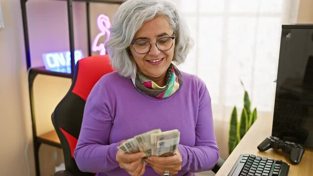 Grey-haired woman counting polish zloty in a gaming room with neon lights, symbolizing a mix of finance and technology.