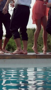 Vertical video of friends standing by a poolside, ready to jump in, with copy space