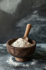 Wooden bowl with white flour powder heap and spoon made of wood, gray background, Generative AI