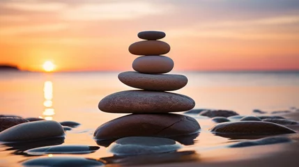 Tuinposter balance stack of zen stones on beach during an emotional and peaceful sunset, golden hour on the beach © Usman