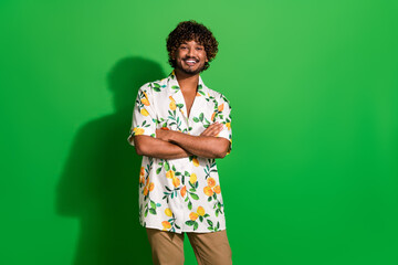 Photo of cheerful good mood arabian man wear print shirt arms folded empty space isolated green color background