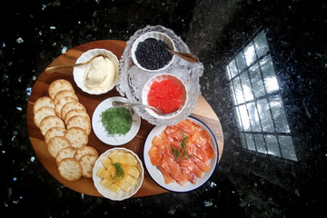Preparation of delicious but expensive red and black caviar with crackers, smoked salmon, dill, lemon and cream