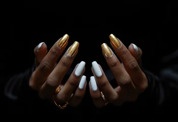  a woman's black and gold manicured hands with white nails on a black background © olegganko